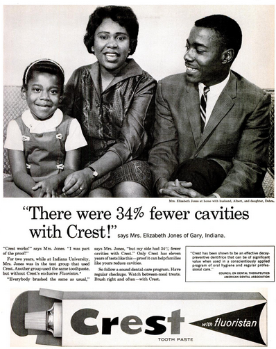 African-American parents and daughter sitting on their couch. Mother is quoted, 'There were 34% fewer cavities with Crest!' says Mrs. Elizabeth Jones of Gary, Indiana.  Additional copy and image of Crest toothpaste in box below.
