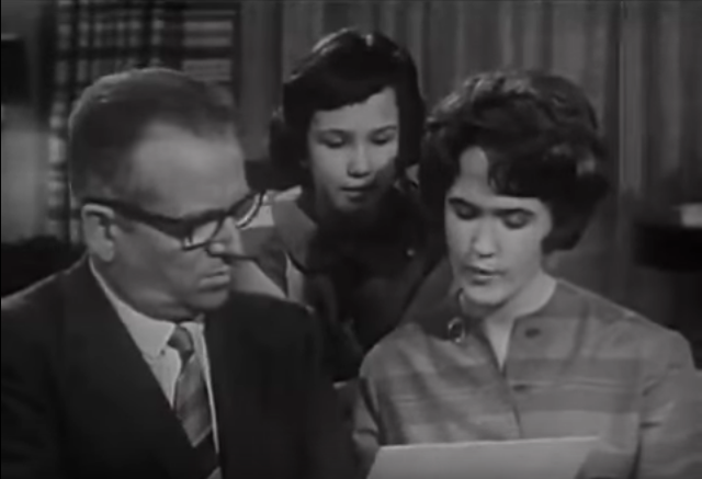 Screenshot from a 1960s television ad for Crest featuring an interviewer TV dude interviewing a White family about how Crest did for their teen daughter's participation in the tests. Teen daughter shows results on a handout to the interviewer guy while younger sister looks on over her shoulder.