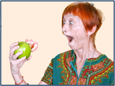 Cheeky redhead woman looking at her dentures popped out stuck in an apple she was biting into