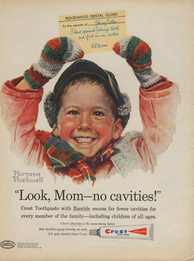 Kid in red coat, knitted mittens, and warm winter cap and scarf, holds a note from Ridgewood Dental Clinic over his head. Slogan and writing below say Look, Mom - no cavities! Crest Toothpaste with fluoride means far fewer cavities for every member of the family - including children of all ages. Crest's fluoride is the same decay fighter that dentists apply directly on teeth. Ask your dentist about Crest.