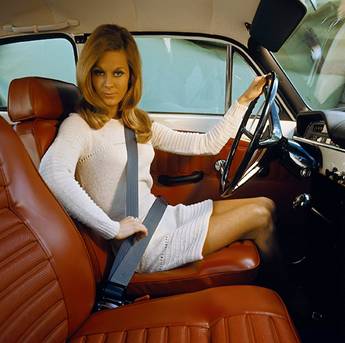 Historic Volvo ad promoting seat belts - woman looks at camera while buckling her 3-point seat belt